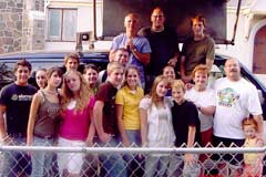 Large group of student missionaries posing with out staff in front of an OAC van